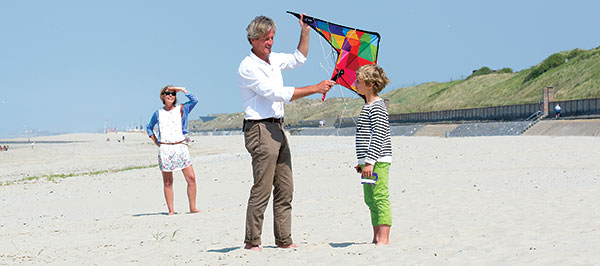 grandparents-and-boy-playing-kite-on-beach